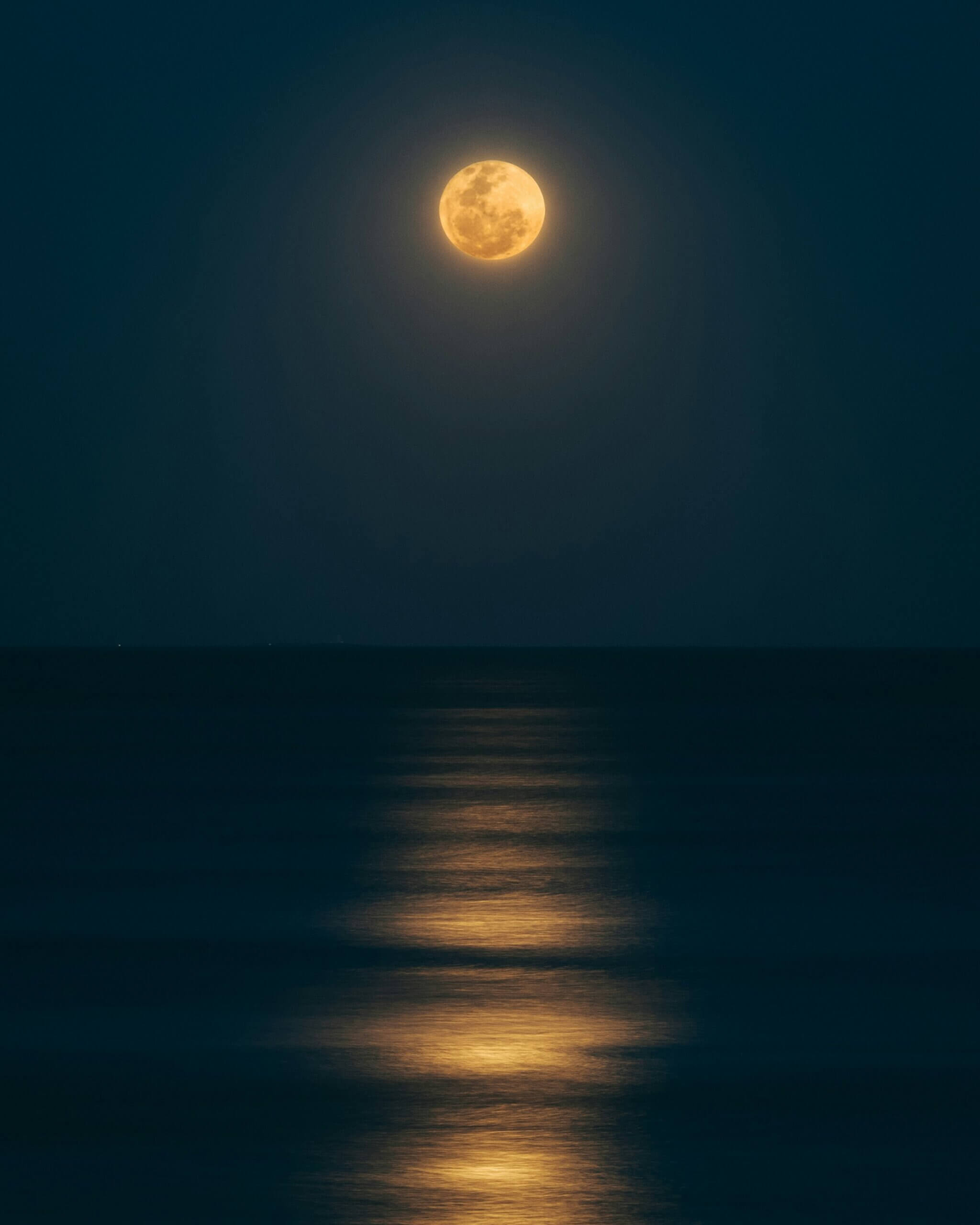 A full moon rising over a body of water